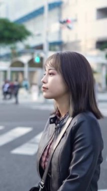 Okinawa 'nın Naha şehrindeki Kokusai Caddesi' nde 20 'li yaşlarının başında genç bir Japon kadının ağır çekim dikey videosu.