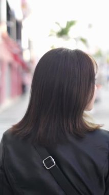 Okinawa 'nın Naha şehrindeki Kokusai Caddesi' nde 20 'li yaşlarının başında genç bir Japon kadının ağır çekim dikey videosu.