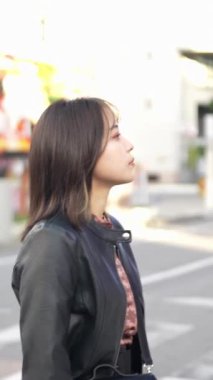 Okinawa 'nın Naha şehrindeki Kokusai Caddesi' nde 20 'li yaşlarının başında genç bir Japon kadının ağır çekim dikey videosu.