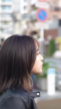 Okinawa 'nın Naha şehrindeki Kokusai Caddesi' nde 20 'li yaşlarının başında genç bir Japon kadının ağır çekim dikey videosu.