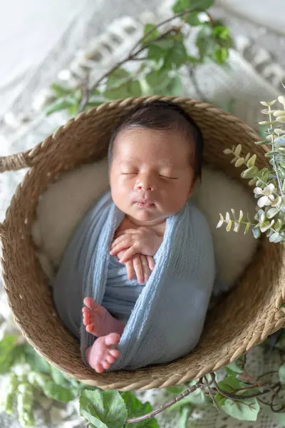 Newborn photography of a Taiwanese and half-Australian half-born 8 days old newborn baby sleeping in a basket wrapped in a blue wrap