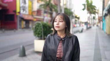 Okinawa bölgesinden genç bir Japon kadın 20 'li yaşlarda Naha City, Okinawa' da Kokusai Caddesi 'nde tek başına yürüyor.