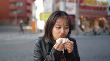 Okinawa bölgesinden genç bir Japon kadın 20 'li yaşlarda, kışlık kıyafetleriyle sokak yemekleri yiyor. Naha City, Okinawa' da Kokusai Caddesi 'nde bir sürü sataandagi var.