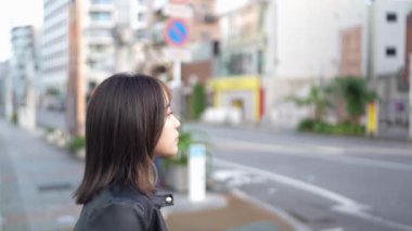 Okinawa 'nın Naha şehrinin Kokusai Caddesi yakınlarındaki bir alışveriş sokağında 20' li yaşlarda, kışın gezen bir kadının yavaş çekim videosu.