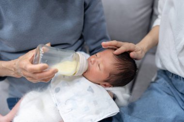 70 'li yaşlarında Tayvanlı bir büyükannede bebek şişesinde süt içen 8 günlük bir bebek.