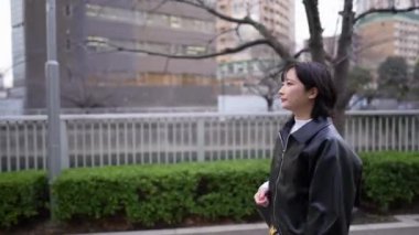 20 'li yaşlarda Japon bir kadın kışın Tokyo' da, Shinagawa 'da Gotanda İstasyonu' nun etrafında yürüyor.