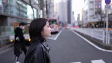 20 'li yaşlarda Japon bir kadın kışın Tokyo' da, Shinagawa 'da Gotanda İstasyonu' nun etrafında yürüyor.