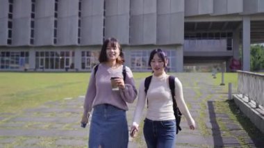 Tayvan 'ın Taipei şehrinde Wenshan Bölgesi' nde kampüste konuşurken 20 'li yaşlarda iki Tayvanlı kız öğrenci yürüyor.