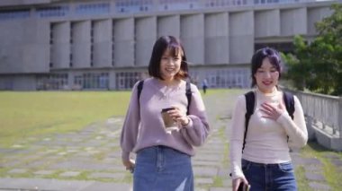 Tayvan 'ın Taipei şehrinde Wenshan Bölgesi' nde kampüste konuşurken 20 'li yaşlarda iki Tayvanlı kız öğrenci yürüyor.