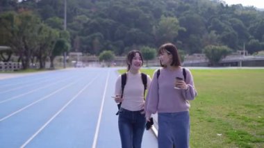 Tayvan 'ın Taipei şehrinde Wenshan Bölgesi' nde kampüste konuşurken 20 'li yaşlarda iki Tayvanlı kız öğrenci yürüyor.