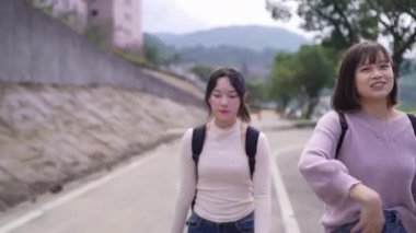 Tayvan 'ın Taipei şehrinde Wenshan Bölgesi' nde kampüste konuşurken 20 'li yaşlarda iki Tayvanlı kız öğrenci yürüyor.