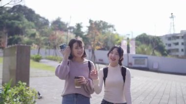 Tayvan 'ın Taipei şehrinde Wenshan Bölgesi' nde kampüste konuşurken 20 'li yaşlarda iki Tayvanlı kız öğrenci yürüyor.