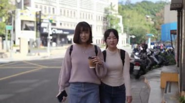 Tayvan 'ın Taipei şehrinde Wenshan Bölgesi' nde kampüste konuşurken 20 'li yaşlarda iki Tayvanlı kız öğrenci yürüyor.