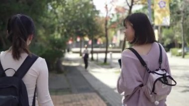 Tayvan 'ın Taipei şehrinde Wenshan Bölgesi' nde kampüste konuşurken 20 'li yaşlarda iki Tayvanlı kız öğrenci yürüyor.