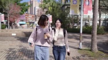 Tayvan 'ın Taipei şehrinde Wenshan Bölgesi' nde kampüste konuşurken 20 'li yaşlarda iki Tayvanlı kız öğrenci yürüyor.