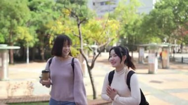 Tayvan 'ın Taipei şehrinde Wenshan Bölgesi' nde kampüste konuşurken 20 'li yaşlarda iki Tayvanlı kız öğrenci yürüyor.