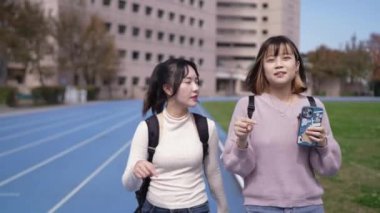 Tayvan 'ın Taipei şehrinde Wenshan Bölgesi' nde kampüste konuşurken 20 'li yaşlarda iki Tayvanlı kız öğrenci yürüyor.