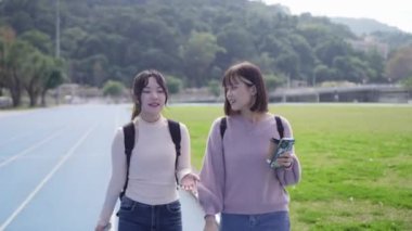 Tayvan 'ın Taipei şehrinde Wenshan Bölgesi' nde kampüste konuşurken 20 'li yaşlarda iki Tayvanlı kız öğrenci yürüyor.