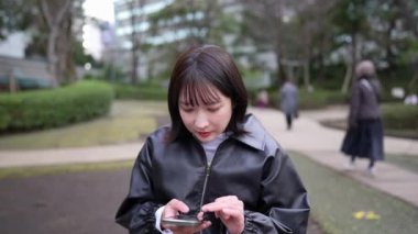 20 'li yaşlarında bir Japon kadın Gotanda İstasyonu yakınlarındaki bir parkta oturuyor.