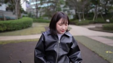 20 'li yaşlarında bir Japon kadın Gotanda İstasyonu yakınlarındaki bir parkta oturuyor.