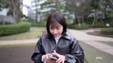 20 'li yaşlarında bir Japon kadın Gotanda İstasyonu yakınlarındaki bir parkta oturuyor.