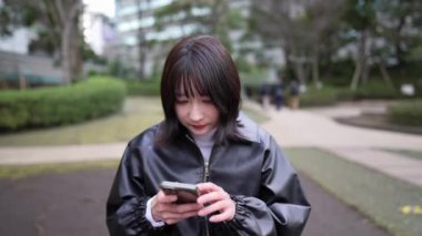 20 'li yaşlarında bir Japon kadın Gotanda İstasyonu yakınlarındaki bir parkta oturuyor.