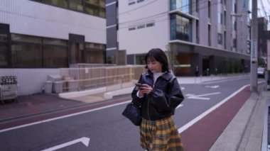 Japon bir kadının kışın akıllı telefonunu kullanırken Gotanda İstasyonu, Shinagawa-ku, Tokyo 'da dolaştığı yavaş çekim videosu.