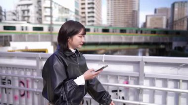 Japon bir kadının kışın akıllı telefonunu kullanırken Gotanda İstasyonu, Shinagawa-ku, Tokyo 'da dolaştığı yavaş çekim videosu.