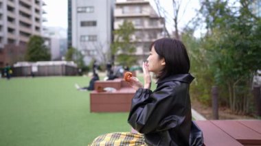 Yavaş çekimde, 20 'li yaşlarda genç bir Japon kadının Gotanda İstasyonu, Shinagawa-ku, Tokyo' da kışın yediği churros videosu.