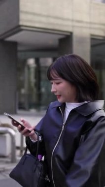 20 'li yaşlarında genç bir Japon kadının kışın akıllı telefonuyla Gotanda İstasyonu, Shinagawa-ku, Tokyo' da dolaştığı dikey bir video.