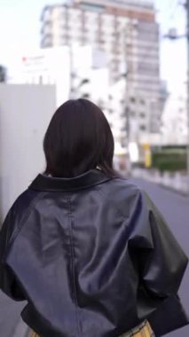 20 'li yaşlarında genç bir Japon kadının kışın akıllı telefonuyla Gotanda İstasyonu, Shinagawa-ku, Tokyo' da dolaştığı dikey bir video.