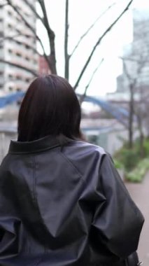 20 'li yaşlarda genç bir Japon kadının kışın Tokyo, Shinagawa' daki Gotanda İstasyonu 'nda yürüdüğü dikey bir video.