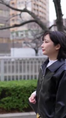 20 'li yaşlarda genç bir Japon kadının kışın Tokyo, Shinagawa' daki Gotanda İstasyonu 'nda yürüdüğü dikey bir video.