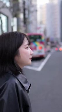 20 'li yaşlarda genç bir Japon kadının kışın Tokyo, Shinagawa' daki Gotanda İstasyonu 'nda yürüdüğü dikey bir video.