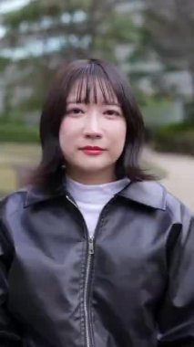 20 'li yaşlarda genç bir Japon kadının Gotanda İstasyonu, Shinagawa-ku, Tokyo' da kışın işaret dili konuşmasının dikey videosu.