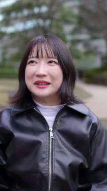 20 'li yaşlarda genç bir Japon kadının Gotanda İstasyonu, Shinagawa-ku, Tokyo' da kışın işaret dili konuşmasının dikey videosu.