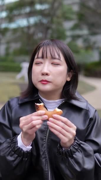 Vídeo Vertical Uma Jovem Japonesa Anos Sentada Comendo Donuts Parque — Vídeo de Stock