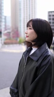 20 'li yaşlarda genç bir Japon kadının kışın Tokyo, Shinagawa' daki Gotanda İstasyonu 'nda dikey videosu.