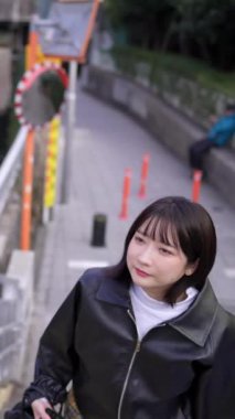 20 'li yaşlarda Japon bir kadının kışın Tokyo, Shinagawa' daki Gotanda İstasyonu 'nun merdivenlerinde yürüdüğünü gösteren dikey bir video.