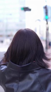 Japon bir kadının kışın akıllı telefonunu kullanırken Gotanda İstasyonu, Shinagawa-ku, Tokyo 'da dolaştığını gösteren dikey yavaş çekim videosu.