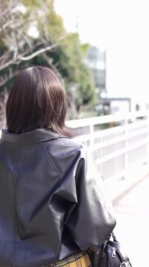 Japon bir kadının kışın akıllı telefonunu kullanırken Gotanda İstasyonu, Shinagawa-ku, Tokyo 'da dolaştığını gösteren dikey yavaş çekim videosu.