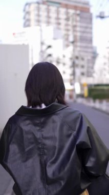Japon bir kadının kışın akıllı telefonunu kullanırken Gotanda İstasyonu, Shinagawa-ku, Tokyo 'da dolaştığını gösteren dikey yavaş çekim videosu.