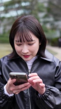 Japon bir kadının kışın Shinagawa-ku, Tokyo 'daki Gotanda İstasyonu yakınlarındaki bir parkta oturduğu dikey yavaş çekim videosu.