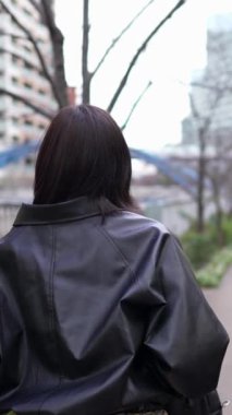 Japon bir kadının kışın Gotanda İstasyonu, Shinagawa-ku, Tokyo 'da yürüdüğünü gösteren dikey yavaş çekim videosu.