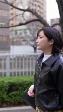 Japon bir kadının kışın Gotanda İstasyonu, Shinagawa-ku, Tokyo 'da yürüdüğünü gösteren dikey yavaş çekim videosu.