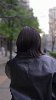 Japon bir kadının kışın Gotanda İstasyonu, Shinagawa-ku, Tokyo 'da yürüdüğünü gösteren dikey yavaş çekim videosu.