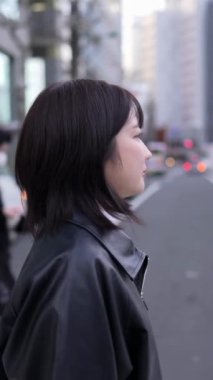 Japon bir kadının kışın Gotanda İstasyonu, Shinagawa-ku, Tokyo 'da yürüdüğünü gösteren dikey yavaş çekim videosu.