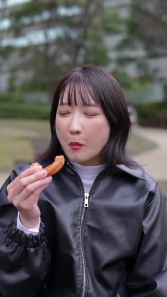 Вертикальное Замедленное Видео Японская Женщина Возрасте Лет Ест Чуррос Парке — стоковое видео