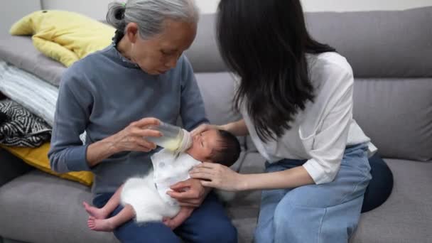 70代の祖母と30代の母親は 白い衣装で8日間の台湾人の赤ちゃんにミルクを与えました — ストック動画