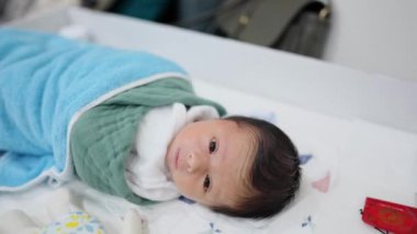 Beyaz kostümlü 8 günlük Tayvanlı bir bebek gözleri açık yatıyor.. 